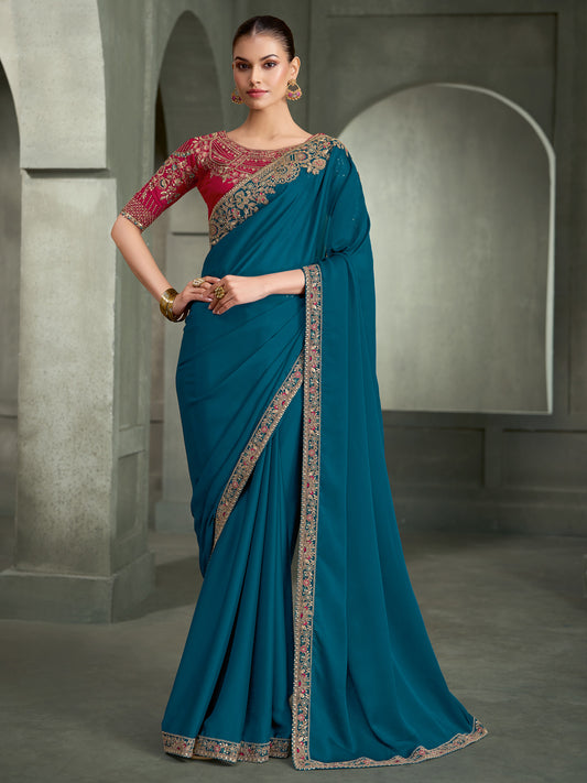 Woman wearing teal blue crepe saree with embroidered motif work and red blouse
