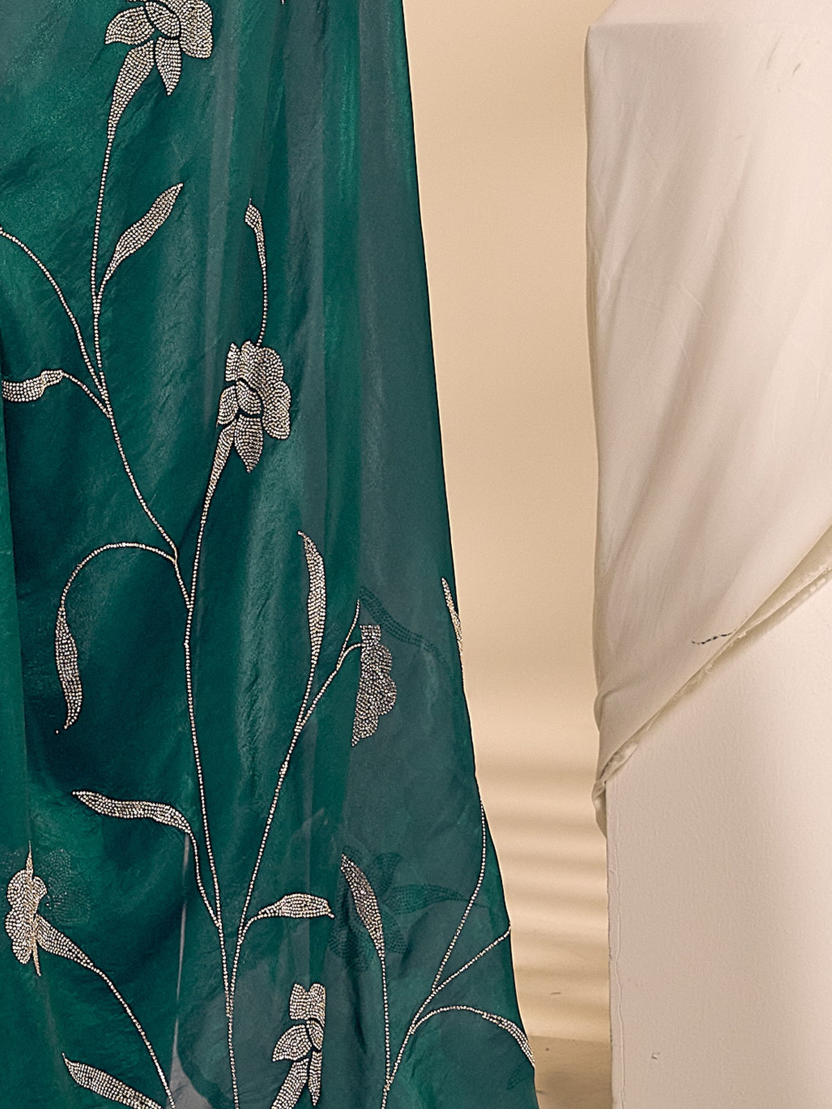 Pallu detail of teal green satin silk saree showing ornamented surface design and embellished border