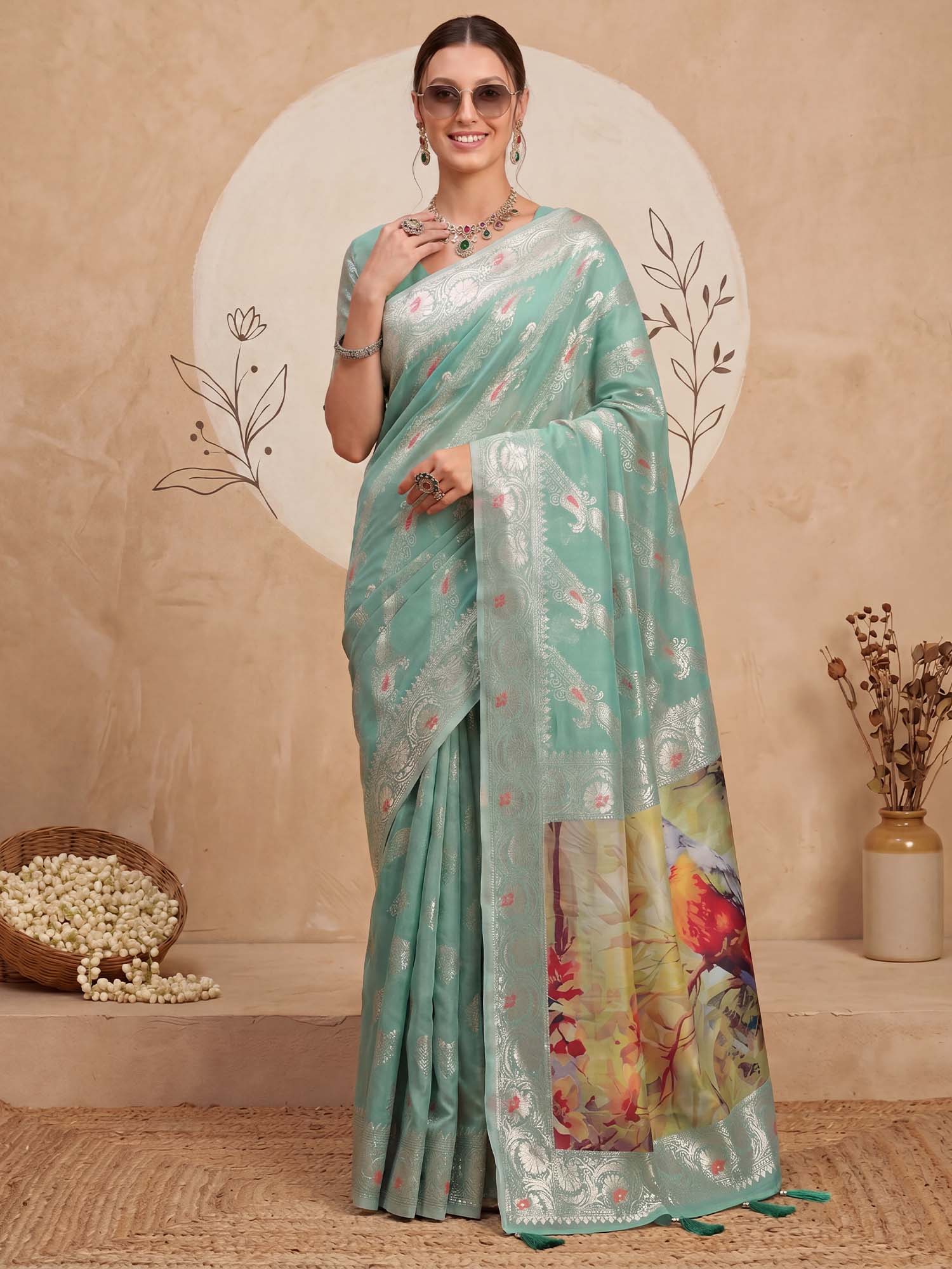 Woman wearing turquoise organza saree with traditional indian motif work and turquoise blouse