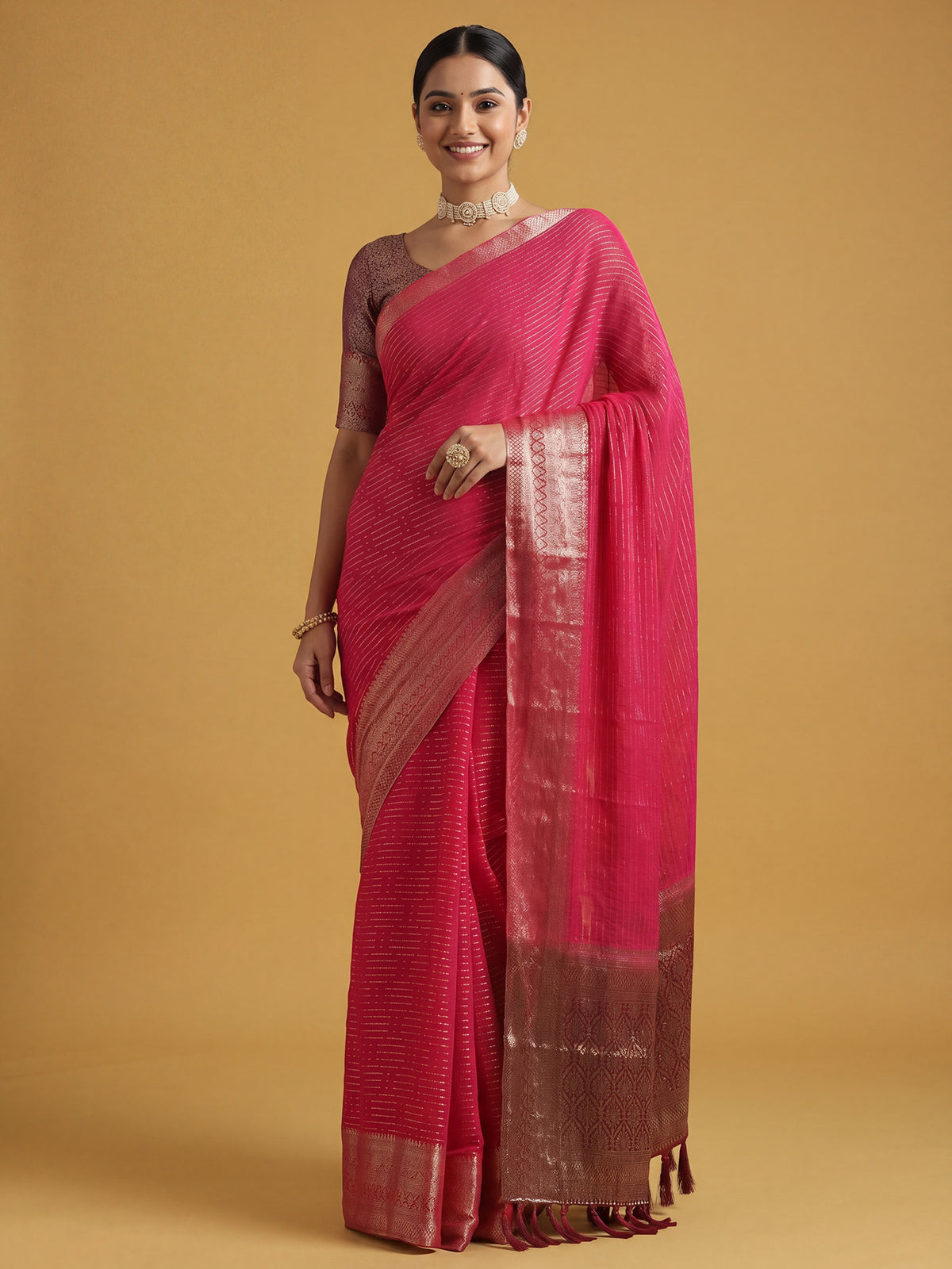 Woman wearing pink chiffon saree with striped pattern design and maroon blouse