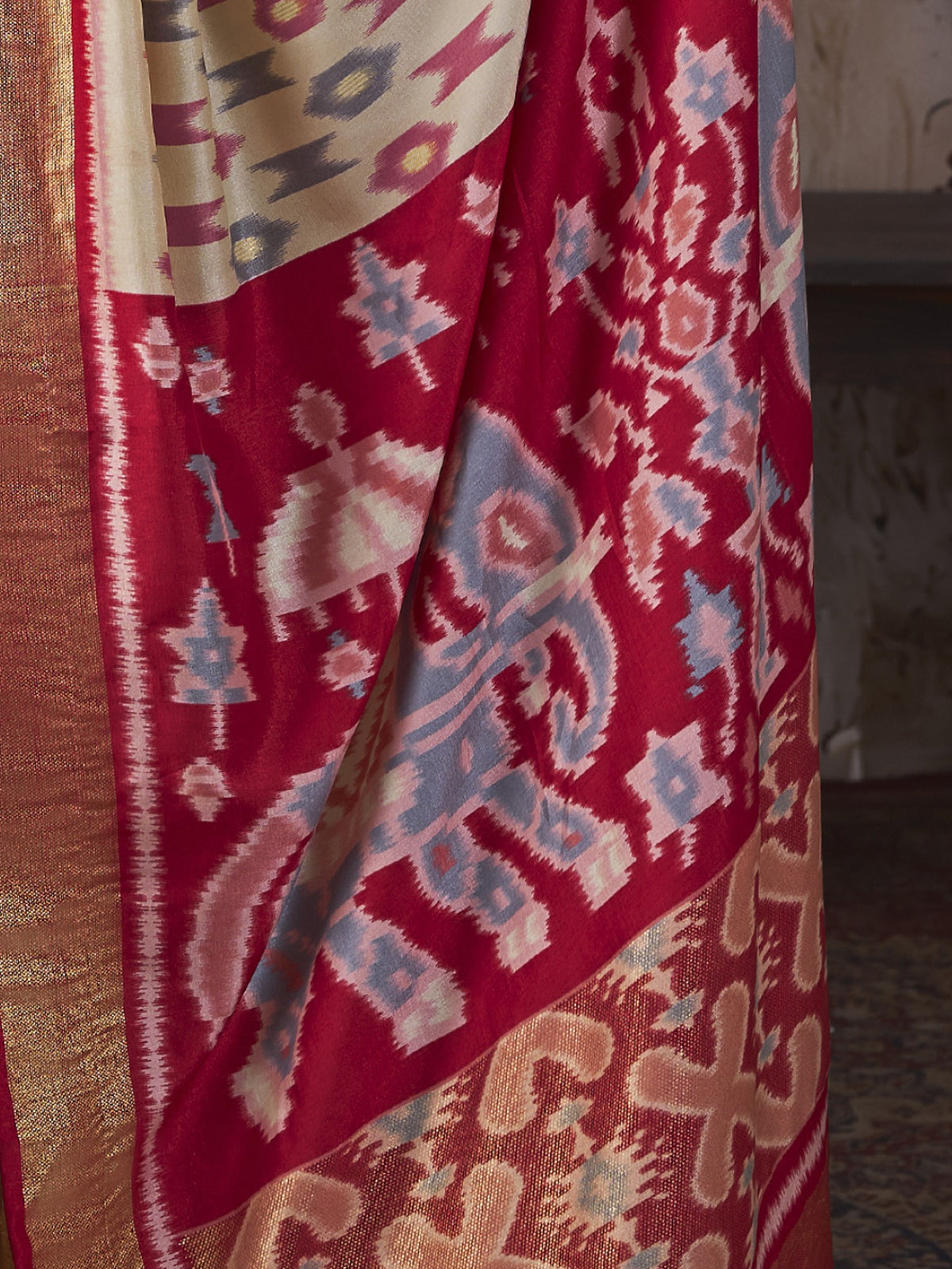 Pallu detail of off white silk blend saree showing ikat resist-dyed pattern and embellished border