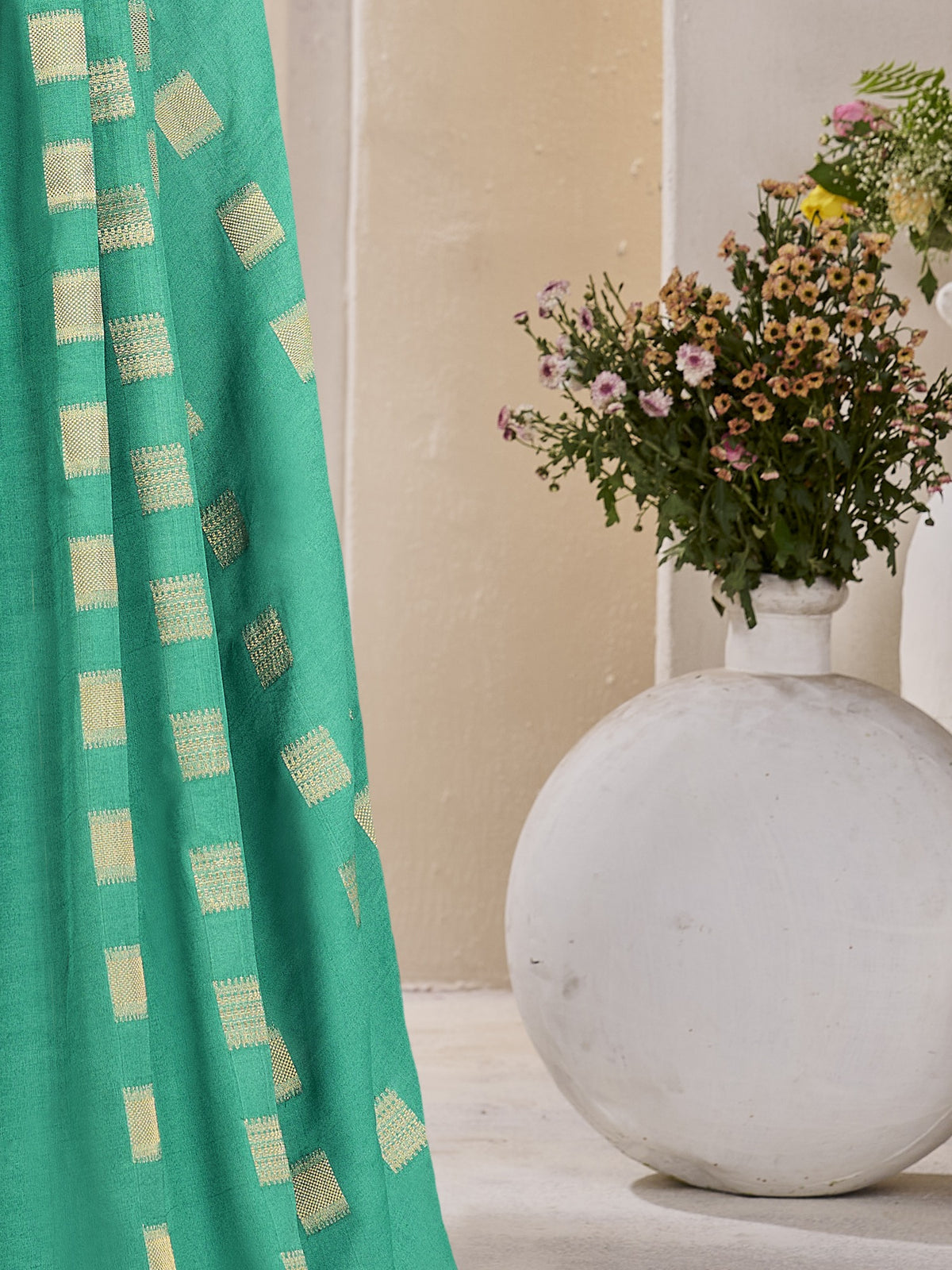 Pallu detail of teal green georgette saree showing zari butta (metallic motif) work and zari border