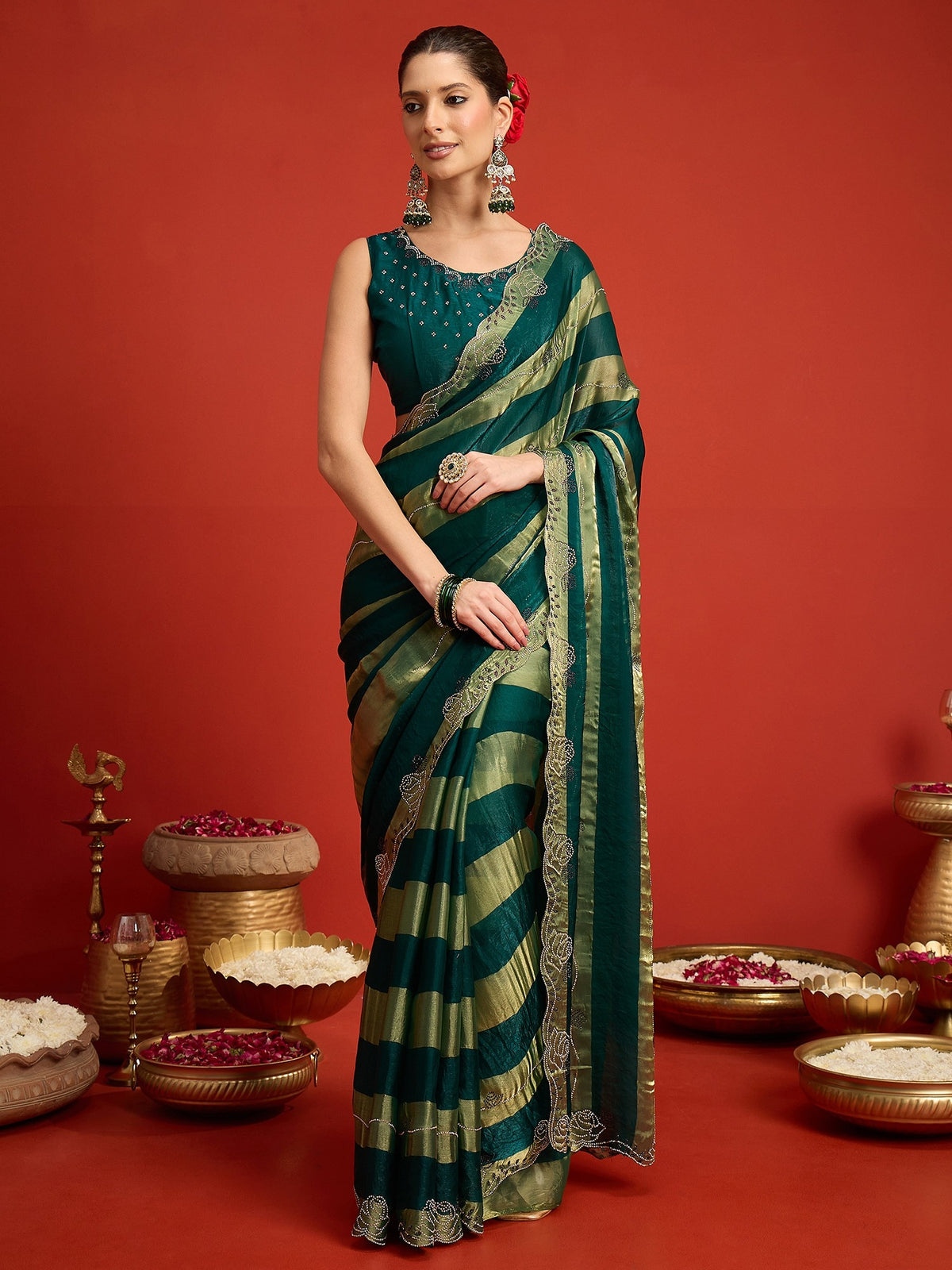 Woman wearing teal green satin silk saree with ornamented surface design and teal green blouse