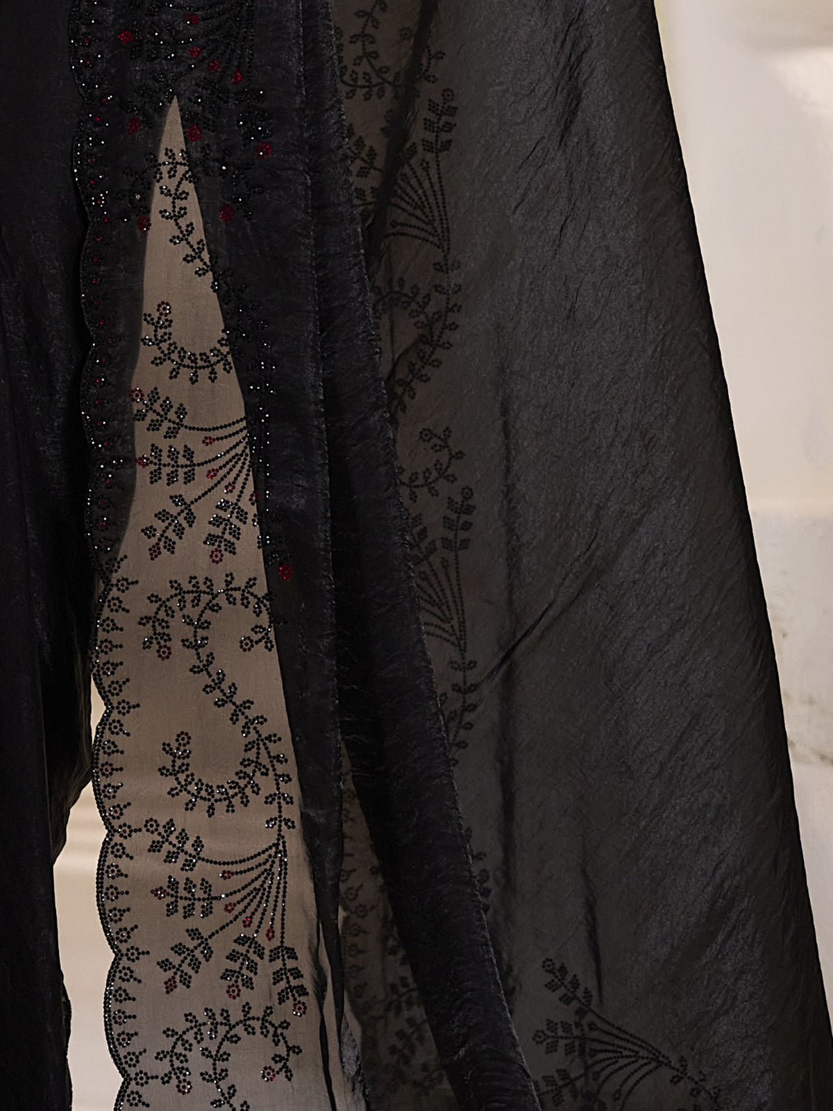 Pallu detail of black satin silk saree showing ornamented surface design and embellished border