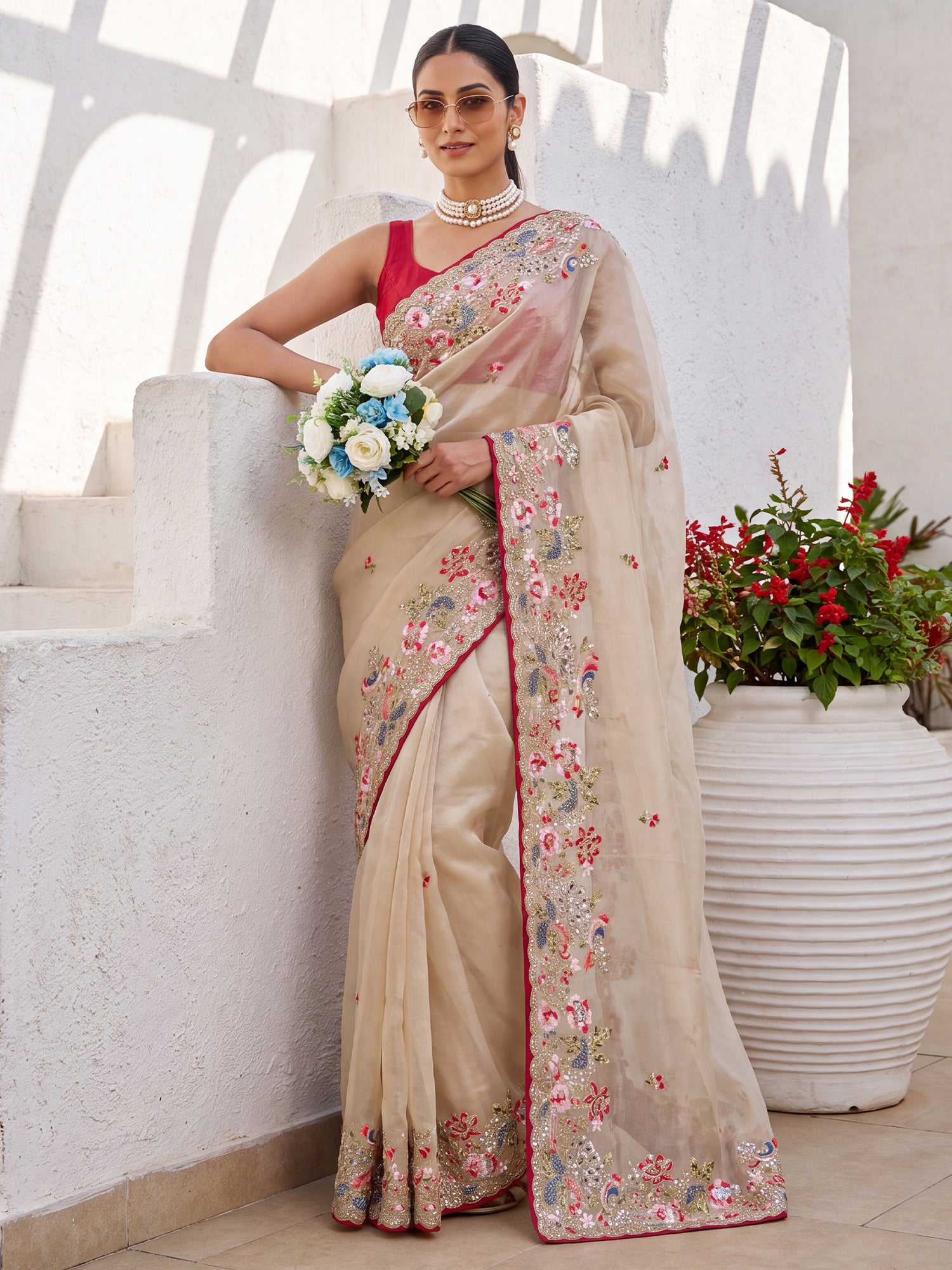 Woman wearing beige organza saree with embroidered motif work and red blouse