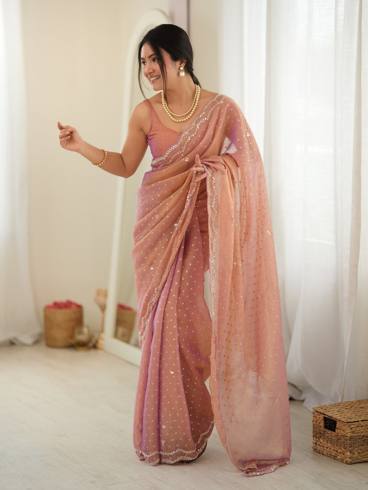 Woman wearing rose gold georgette saree with zari butta (metallic motif) work and rose gold blouse