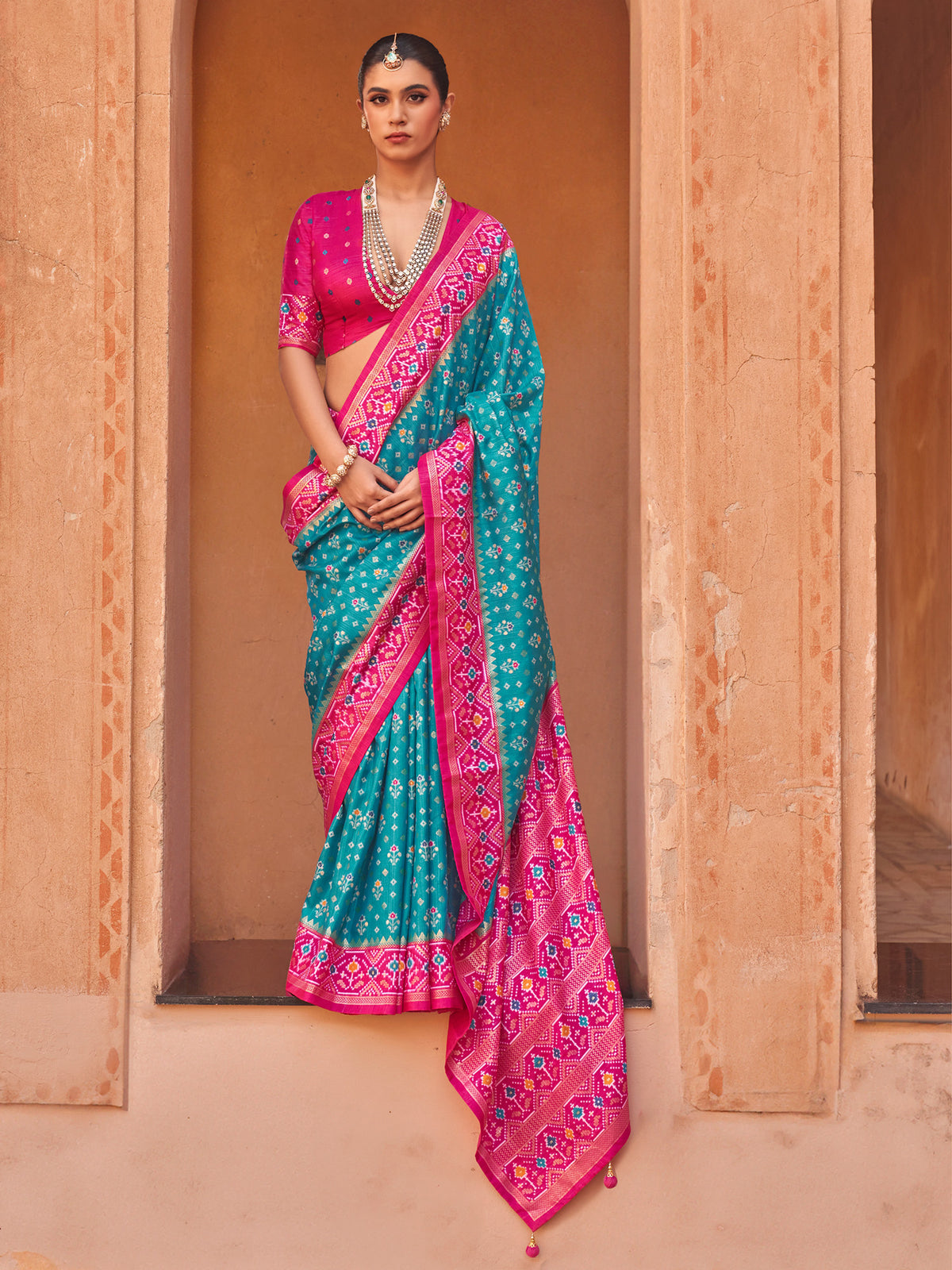 Woman wearing turquoise blue silk blend saree with ikat resist-dyed pattern and pink blouse