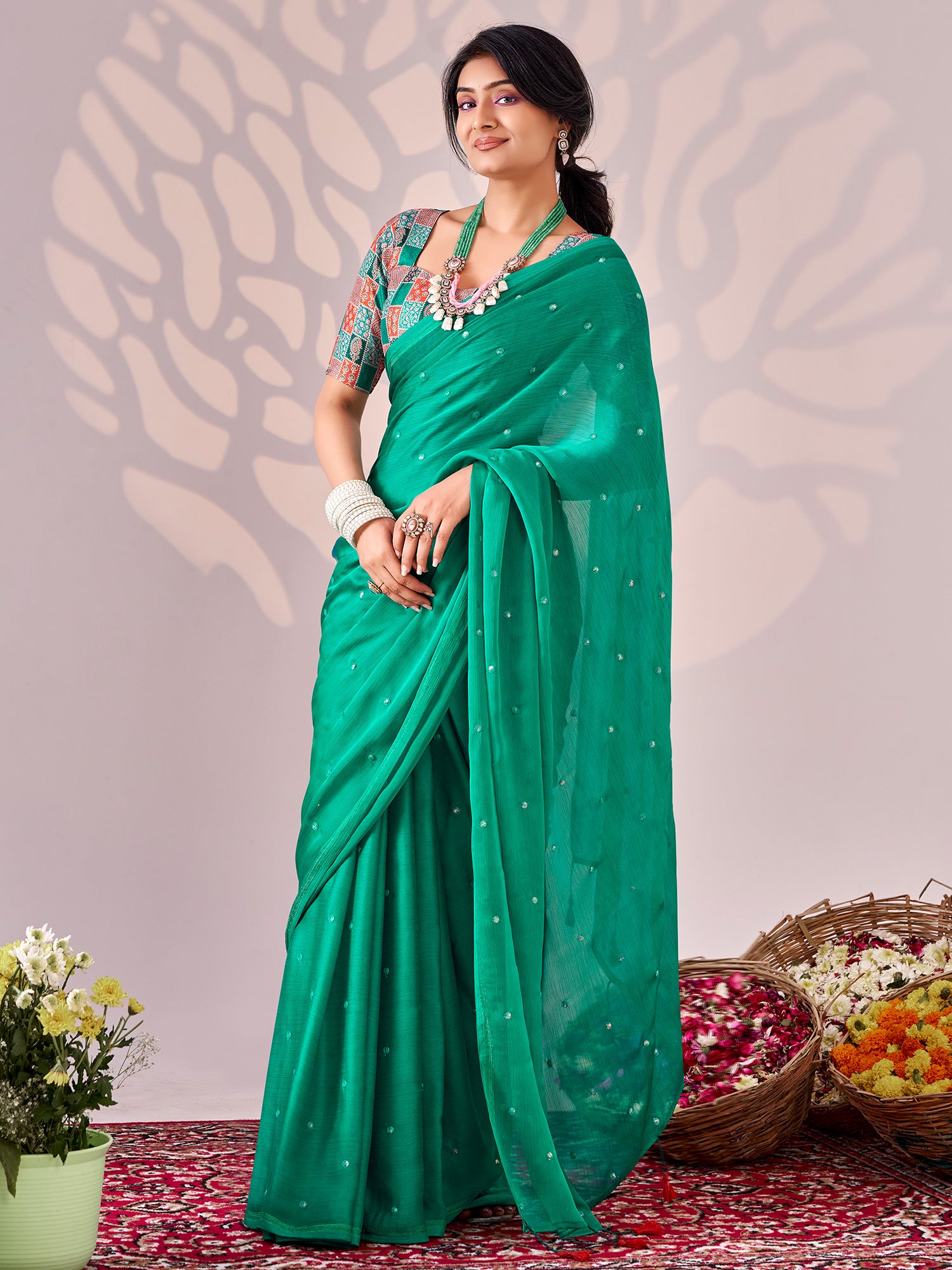 Woman wearing teal green chiffon saree with ornamented surface design and multicolored blouse