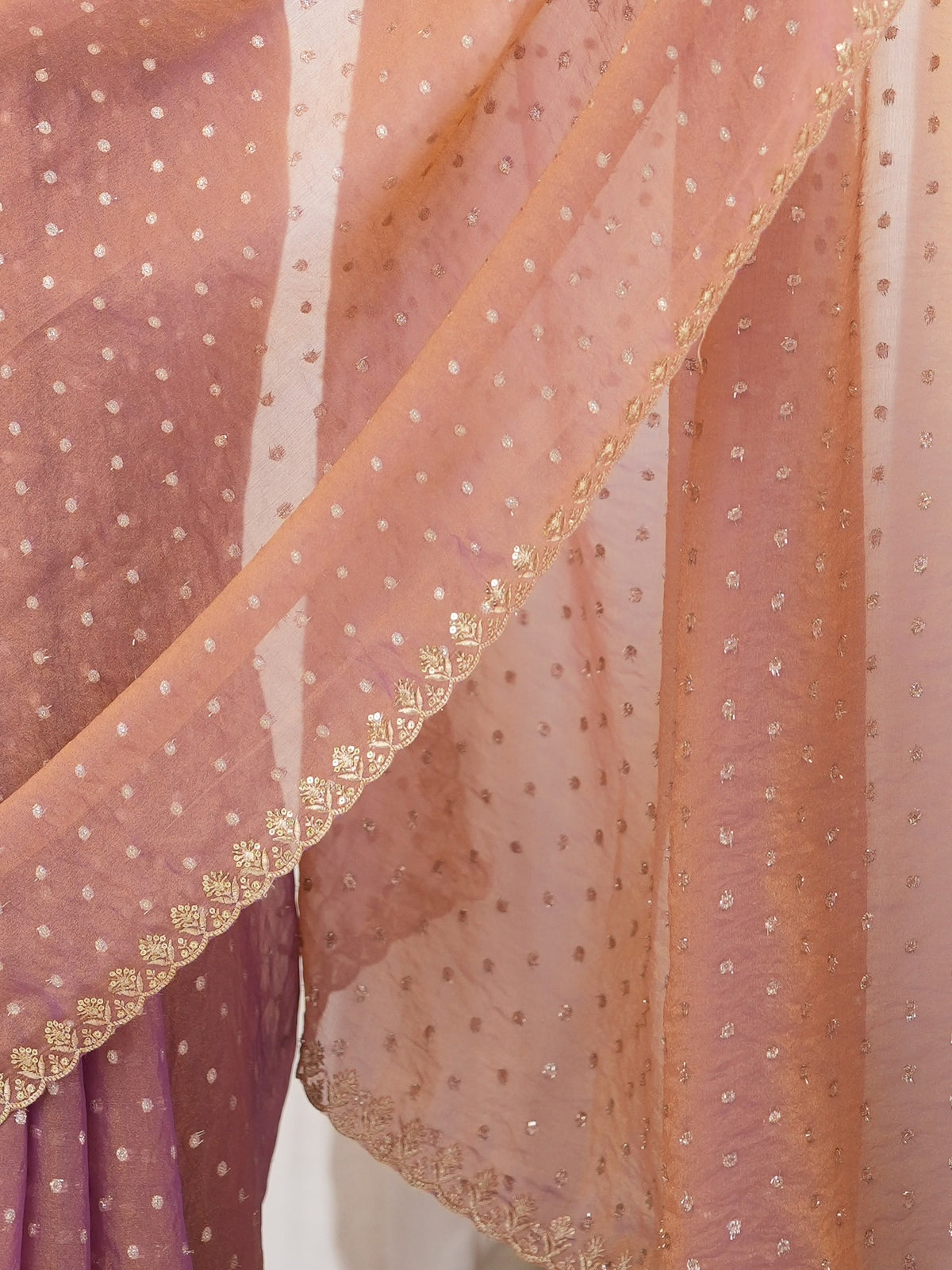 Pallu detail of rose gold georgette saree showing zari butta (metallic motif) work and embellished border