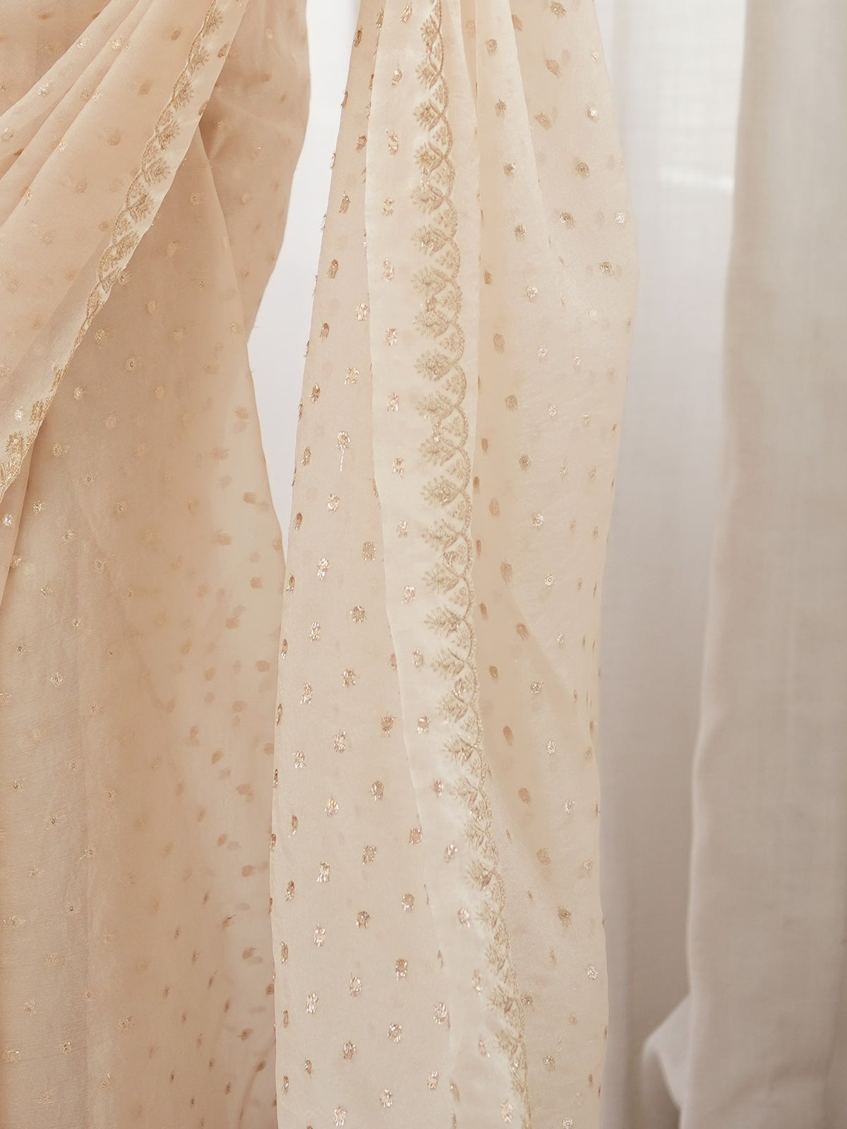 Pallu detail of cream georgette saree showing zari butta (metallic motif) work and embellished border