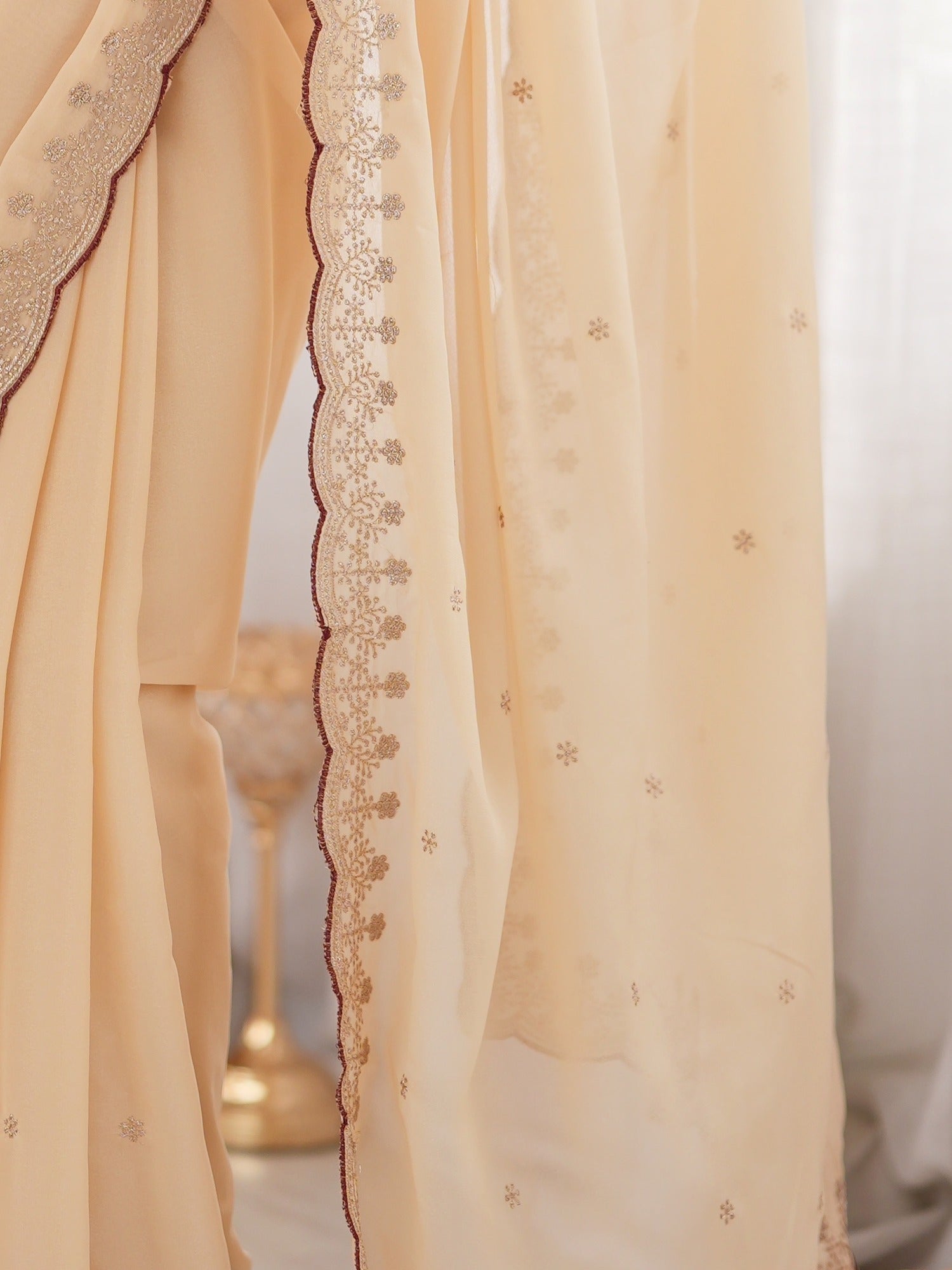 Pallu detail of cream georgette saree showing zari butta (metallic motif) work and zari border