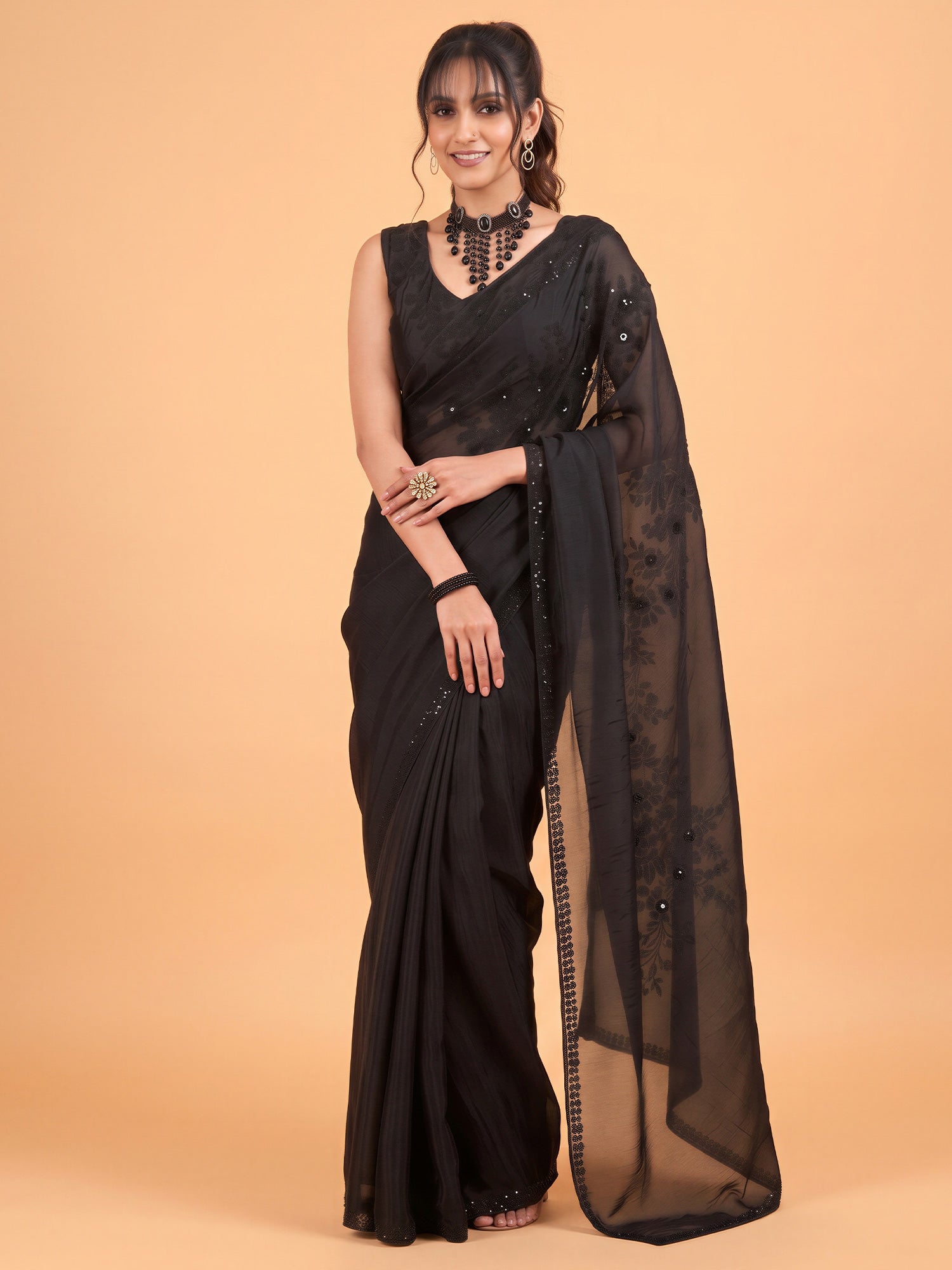 Woman wearing black satin silk saree with ornamented surface design and black blouse