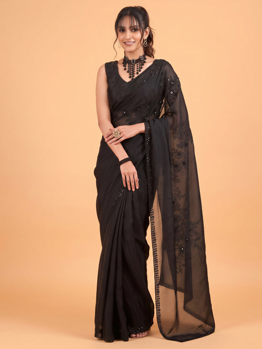 Woman wearing black satin silk saree with ornamented surface design and black blouse