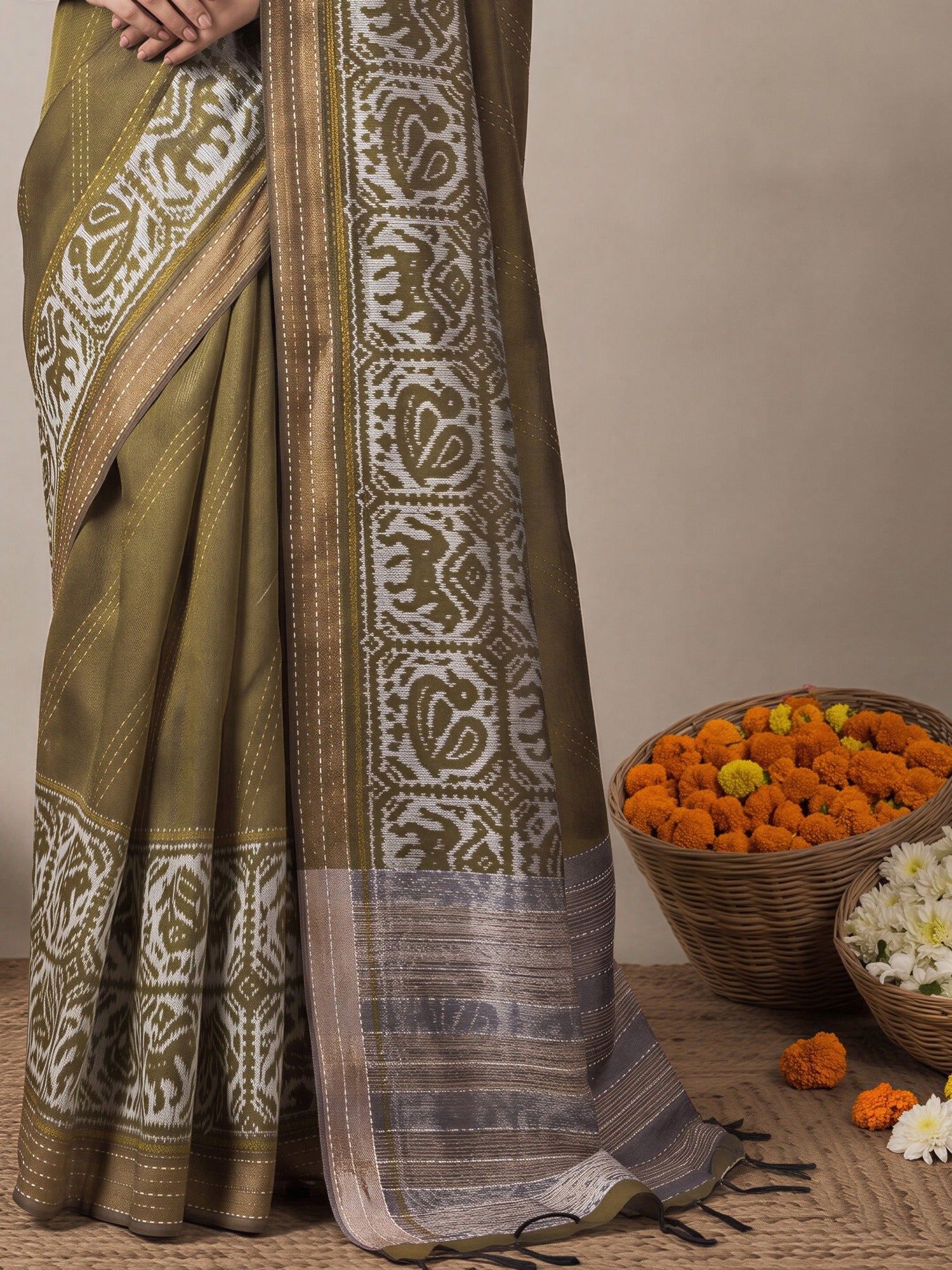 Pallu detail of olive silk cotton saree showing ikat resist-dyed pattern and embroidered border