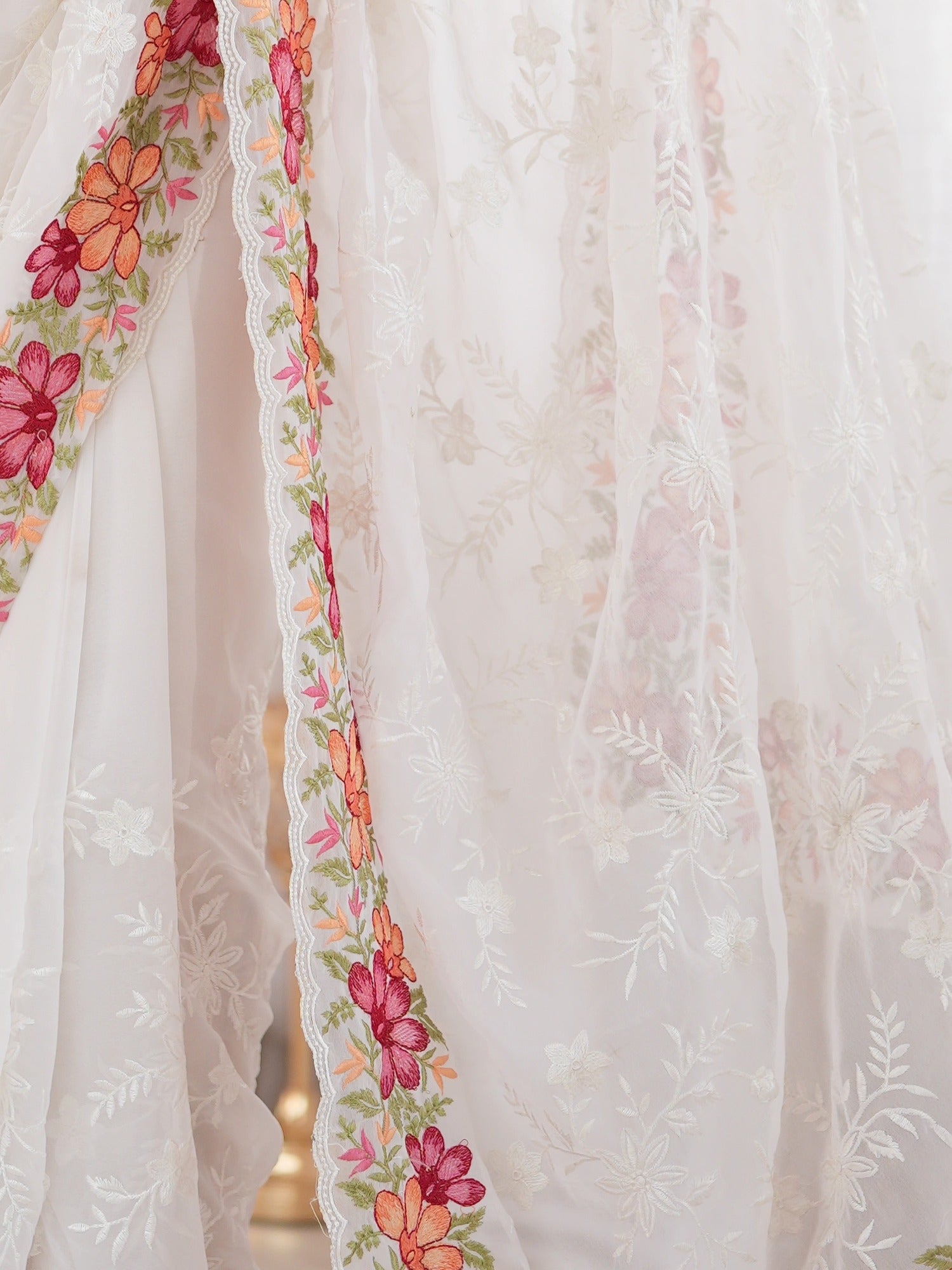 Pallu detail of white georgette saree showing all-over floral design and embroidered border