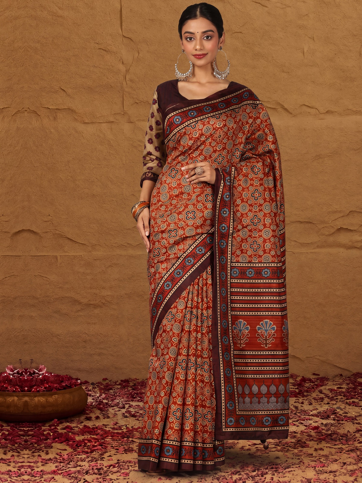 Woman wearing rust silk blend saree with traditional indian motif work and brown blouse