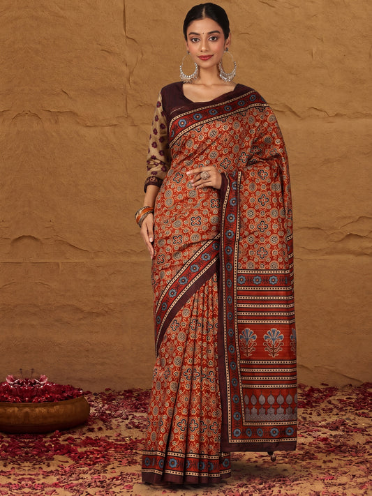 Woman wearing rust silk blend saree with traditional indian motif work and brown blouse