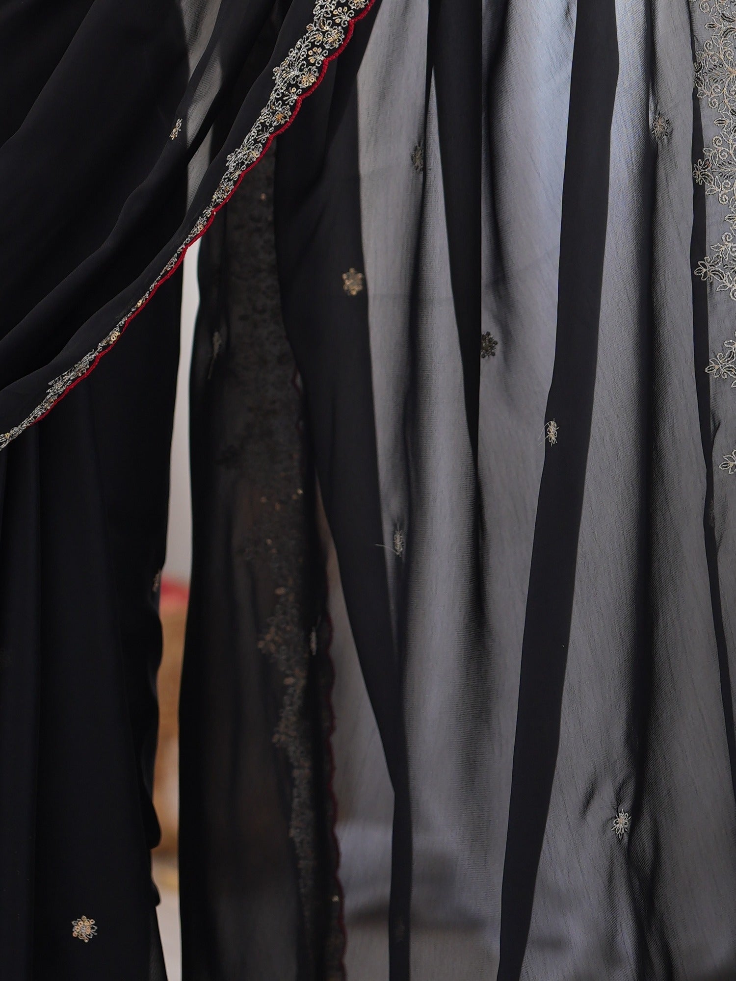 Pallu detail of black georgette saree showing ornamented surface design and scallop border