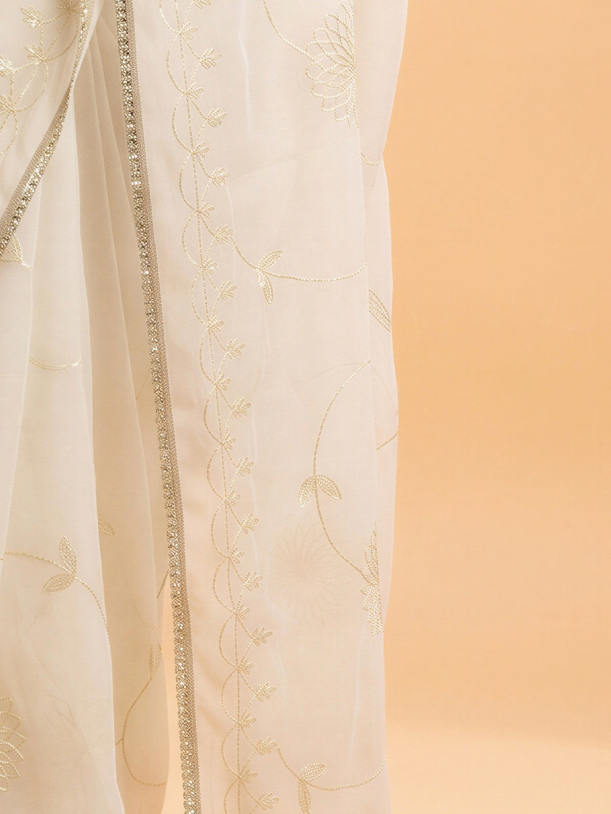 Pallu detail of white georgette saree showing embroidered motif work and embellished border