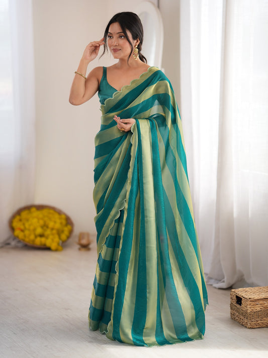 Woman wearing teal green satin saree with striped pattern design and teal green blouse