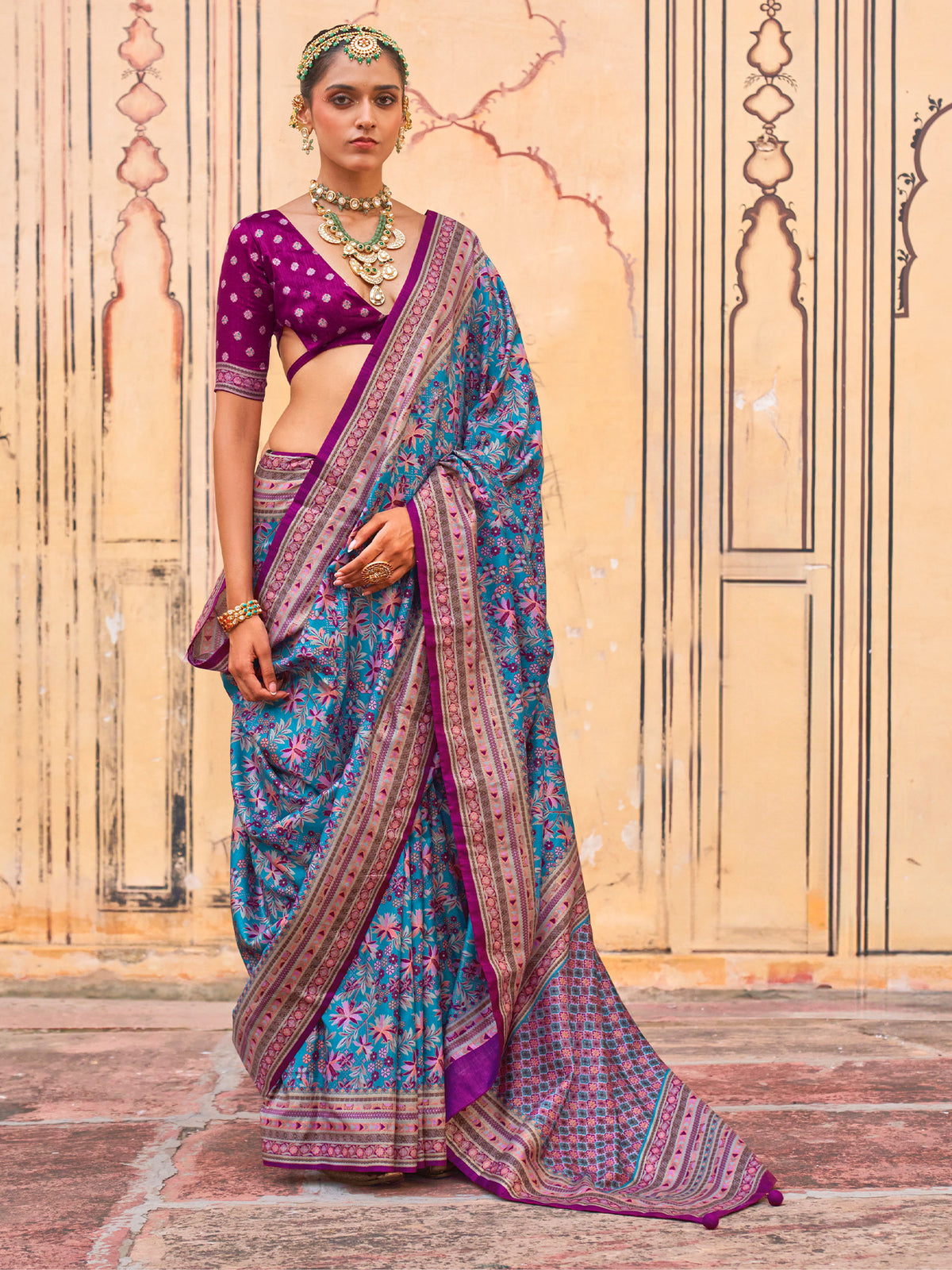 Woman wearing teal blue silk blend saree with kalamkari narrative motif work and purple blouse