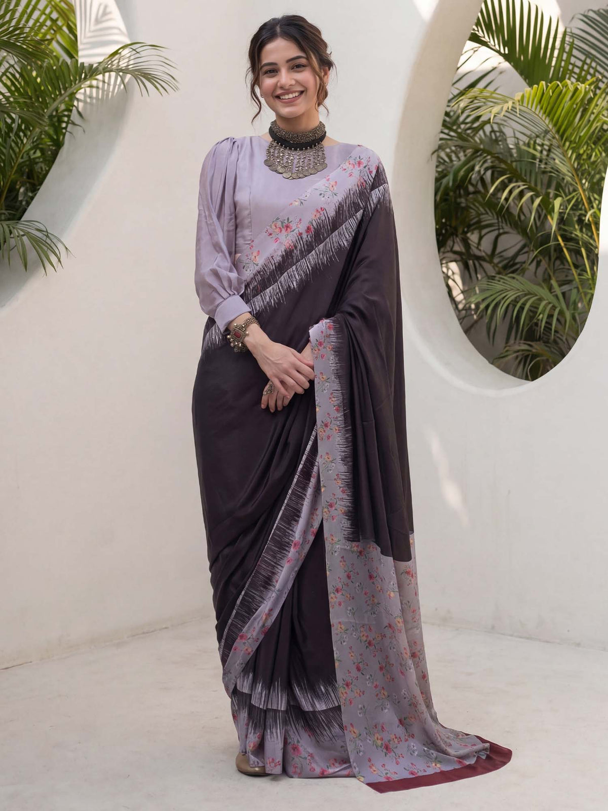 Woman wearing black crepe saree with all-over floral design and lavender blouse