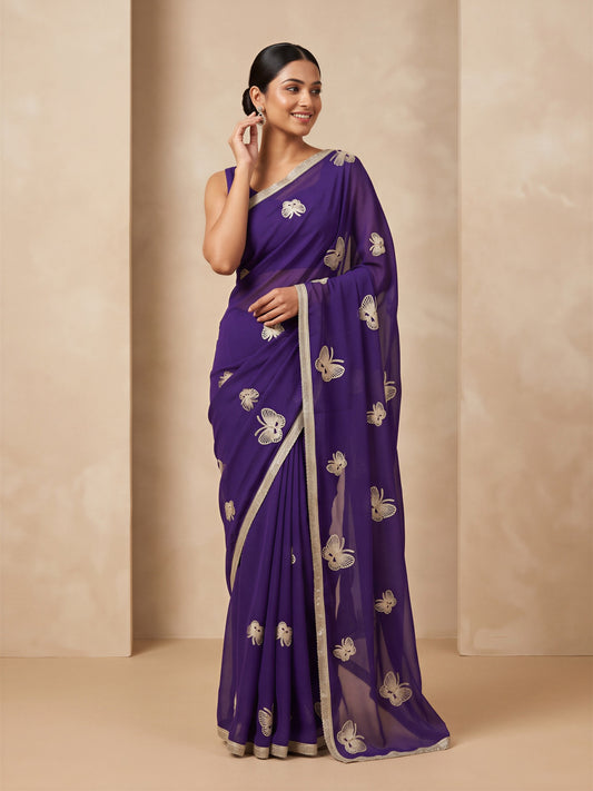 Woman wearing purple georgette saree with embroidered motif work and purple blouse