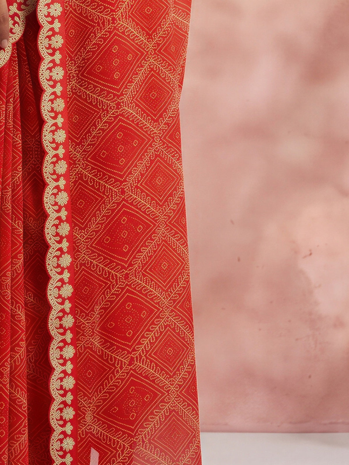 Pallu detail of orange georgette saree showing bandhani tie-dye dot work and embellished border