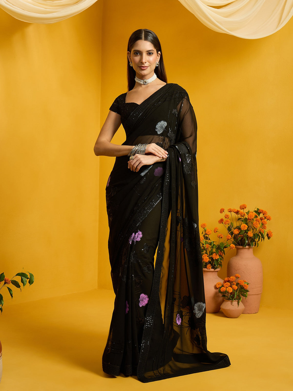 Woman wearing black georgette saree with embroidered motif work and black blouse