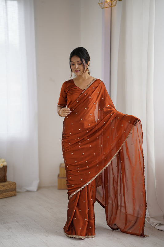 Woman wearing an orange saree with a white blouse in a room.
