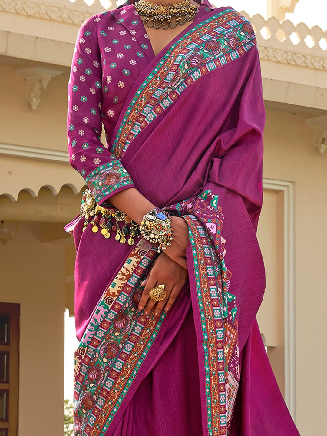 Magenta Patola silk saree with elephant and floral motifs, multicolor Patola border and zari butta work with tassels, worn by model with full-sleeve matching blouse