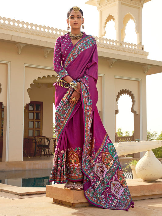 Magenta Patola silk saree with elephant and floral motifs, multicolor Patola border and zari butta work with tassels, worn by model with full-sleeve matching blouse
